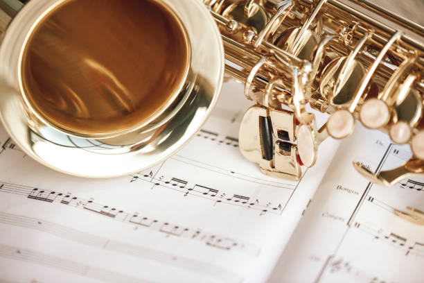 romantischer morgen. nahlick auf saxophon und tasse kaffee auf den musikalischen noten. - close up musical instrument saxophone jazz stock-fotos und bilder