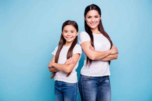 close up photo pretty two people brown haired mum small little daughter crossed arms self-confidently stand back to back ready win winner family games wear t-shirts isolated bright blue background - human teeth child smiling family imagens e fotografias de stock