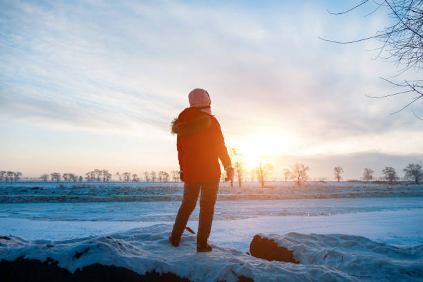 Woman standing by the lakeside in winter.