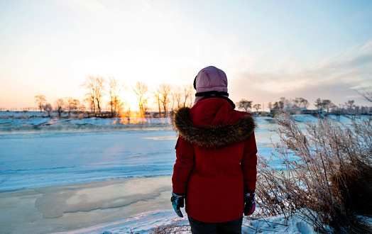 Woman standing by the lakeside in winter.