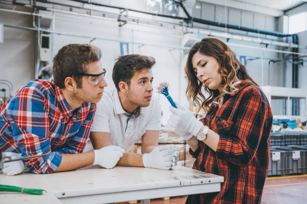 giovani dipendenti del settore che lavorano con attrezzature di produzione - laboratory service electricity scientific experiment foto e immagini stock