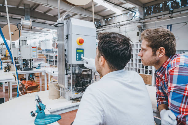 istock Two young engineers men working with manufacturing equipments in factory 1129335682