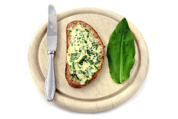 istock dark bread wit fresh wild garlic leaves butter on white isolated background. 1129335852