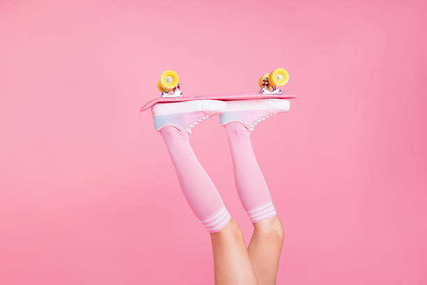 cropped close up photo skinny perfect ideal she her lady legs raised up holding skateboard rolling in air enthusiast isolated pink rose background - shoe women retro revival fashion imagens e fotografias de stock