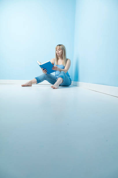 istock Blonde sitting on the floor reading 1129340645
