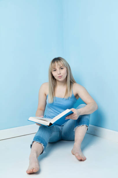 istock Blonde sitting on the floor reading 1129340730