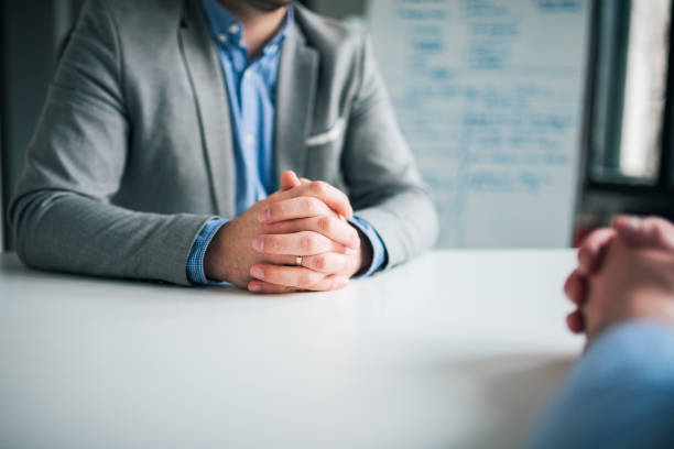 conceito de recrutamento e emprego. duas pessoas de negócio sentado na frente do outro no escritório e discutindo, close-up. - interview business hands clasped confidence - fotografias e filmes do acervo