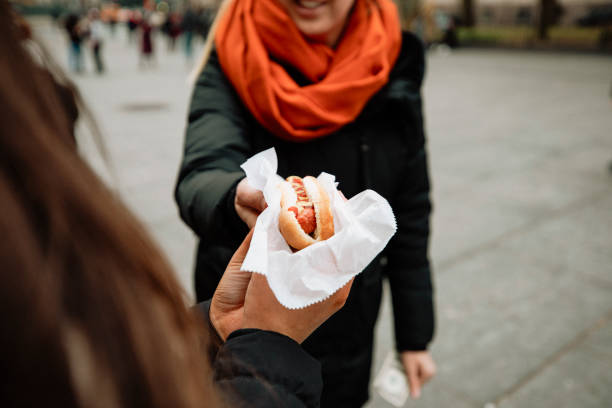 Close-up image of two friends sharing a hot dog.