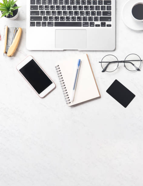 istock Stylized clean marble office working desk with smartphone, laptop, glasses and coffee, workspace design, mock up, top view, flat lay, copy space, closeup 1129344032