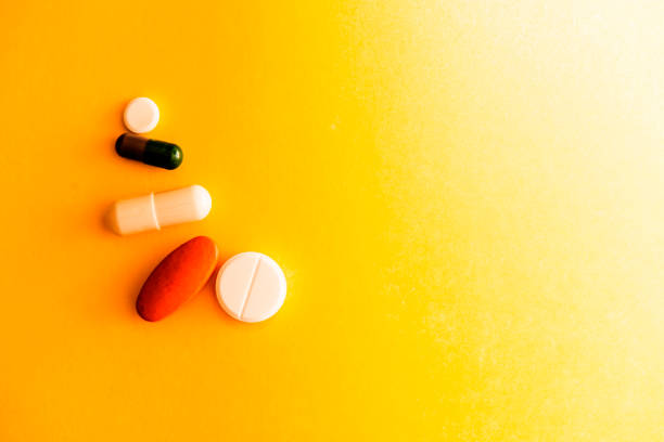 istock Different tablets on a yellow background, medicine, medical capsules of a different form 1129344954