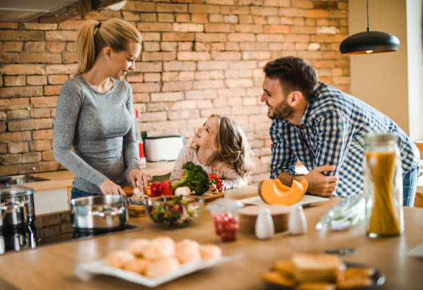 istock Happy family talking while preparing healthy meal in the kitchen. 1129345147