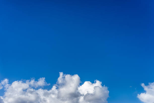 istock Fluffy white clouds against a bright, colorful blue sky 1129347071