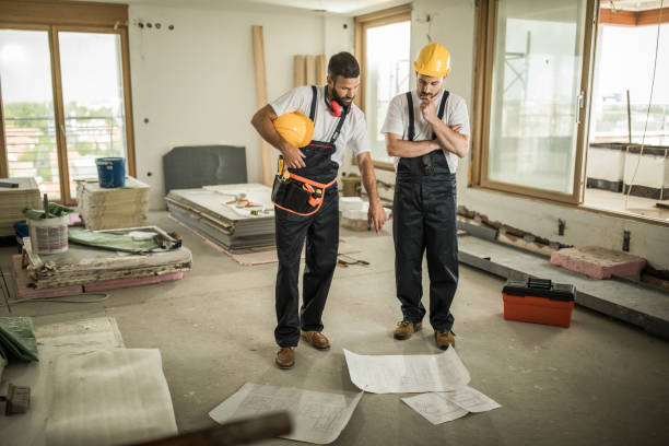 istock Two construction workers analyzing blueprints in renovating apartment. 1129347481