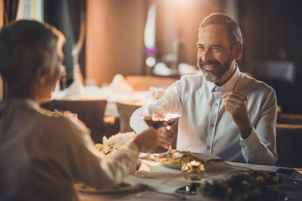 istock Happy mature couple toasting with wine during dinner time in a restaurant. 1129348007