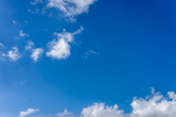 istock Fluffy white clouds against a bright, colorful blue sky 1129348510