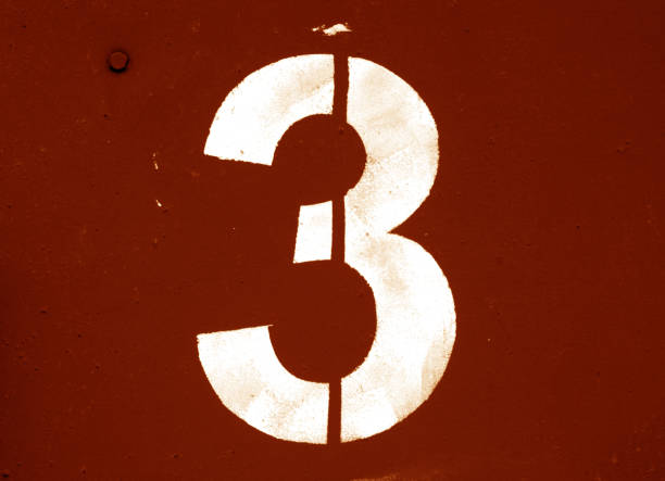 istock Number 3 in stencil on metal wall in orange tone. 1129348543