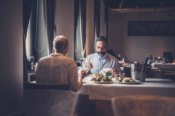istock Senior couple eating dinner in a restaurant. 1129349365