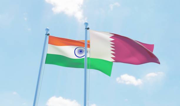 istock Qatar and India, two flags waving against blue sky 1129350560