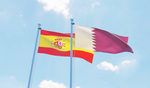 istock Qatar and Spain, two flags waving against blue sky 1129350926