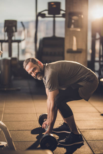 istock Happy senior man having strength exercise with barbell in a gym. 1129352350