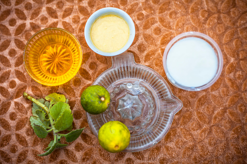 Close up of hair mask for the treatment of aggravated scalp on brown colored surface i.e. yogurt,,honey and lemon juice in a glass bowl.;