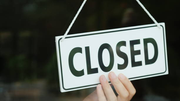 The hand turns the sign with the inscription open to the Closed position. The end of the working day stock photo
