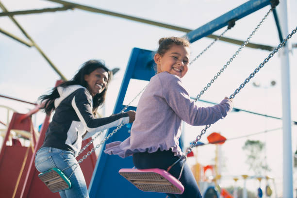 istock Mother and daughter swing on swings. 1129357022