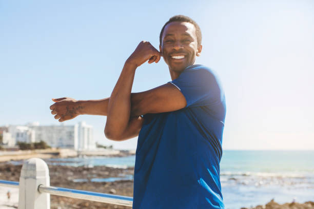 istock Smiling male athlete stretching arms on promenade 1129358516