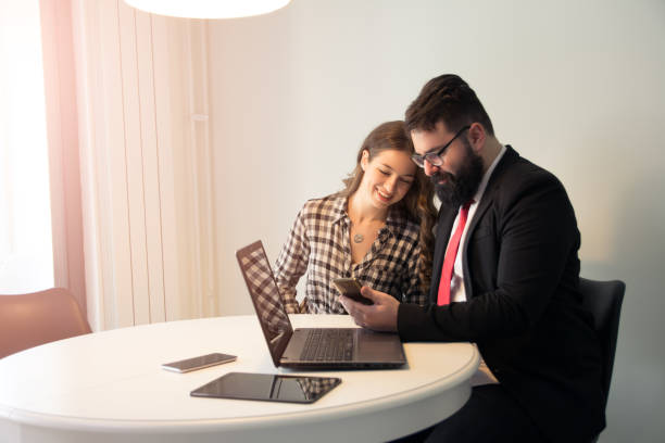 istock Successful hipster with black beard wearing suit working with his beautiful colleague 1129360544