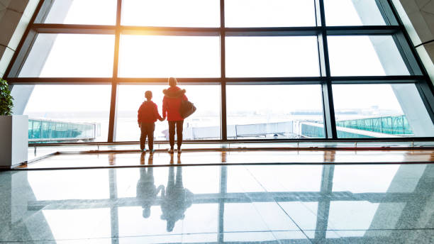 istock Mother and son looking through the window at airport 1129360906