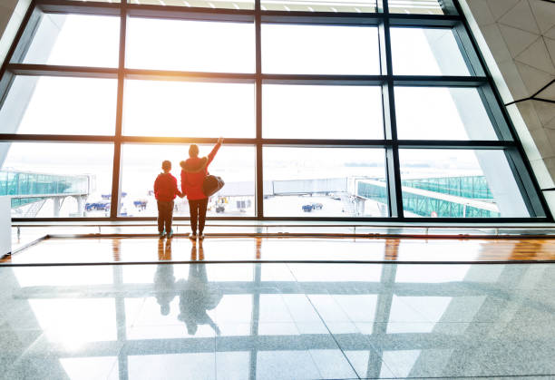 istock Mother and son looking through the window at airport 1129360909