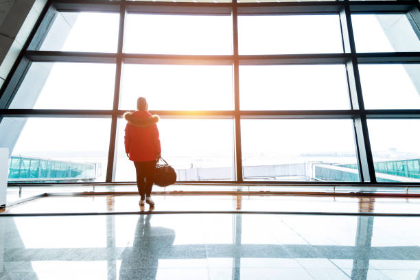 istock Woman looking through the window at  airport 1129360938