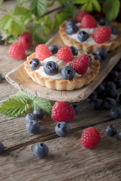 istock Dessert tarts with raspberries and blueberries on a wooden table. 1129364703