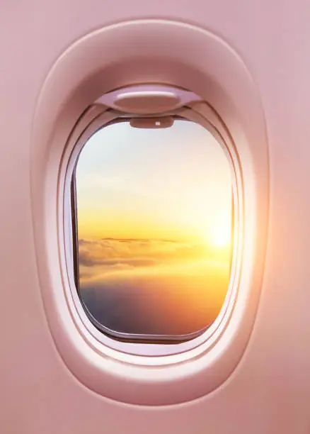 Airplane interior with window view of sunset above clouds. Concept of travel and air transportation