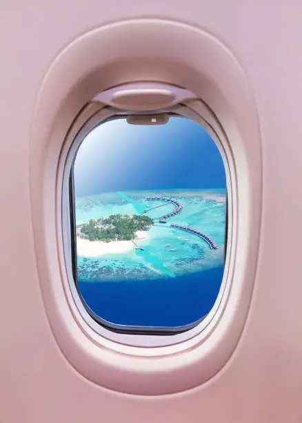 Airplane interior with window view of Maldives island. Concept of travel, beach vacation and air transportation