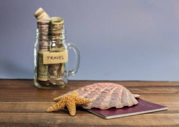 istock Saving money for travel in jar with shell and starfish 1129368381