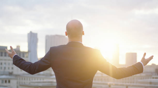 istock Businessman standing on roof. Open arms 1129370201