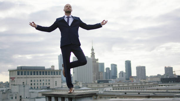 istock Businessman meditating on roof. Tree pose 1129370350