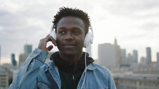 istock Young man listening music on rooftop 1129370364