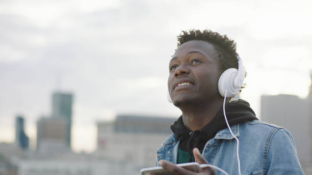 istock Young man listening music from smart phone. Rooftop view 1129370389