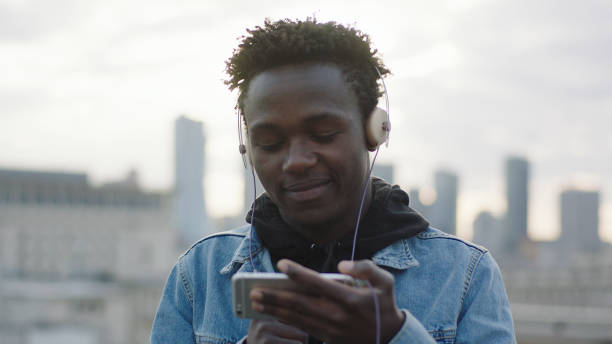 istock Young man listening music from smart phone. Rooftop view 1129370489