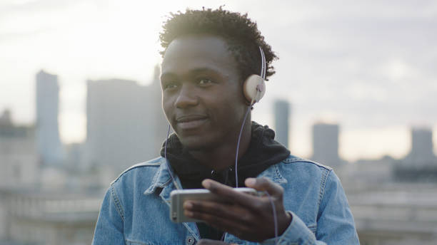 istock Young man listening music from smart phone. Rooftop view 1129370496