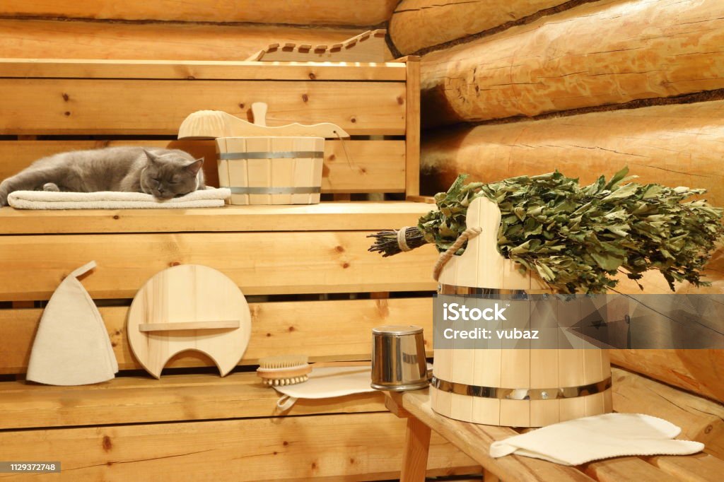Dry birch broom in the sauna. Dry birch broom on the wooden bucket and bath accessories in the sauna. Sauna Stock Photo
