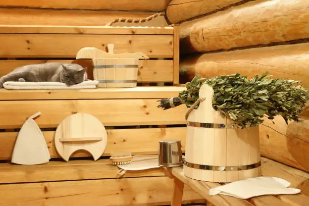 Dry birch broom on the wooden bucket and bath accessories in the sauna.