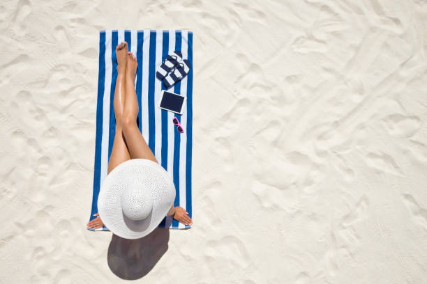 concept de mode de vacances d’été - portant chapeau femme sur la plage sur un sable blanc tiré de dessus de bronzage - deck chair photos et images de collection