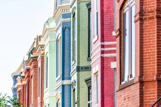 Row of colorful red green and blue painted brick residential townhouses homes houses architecture exterior in Washington DC Capitol Hill neighborhood district