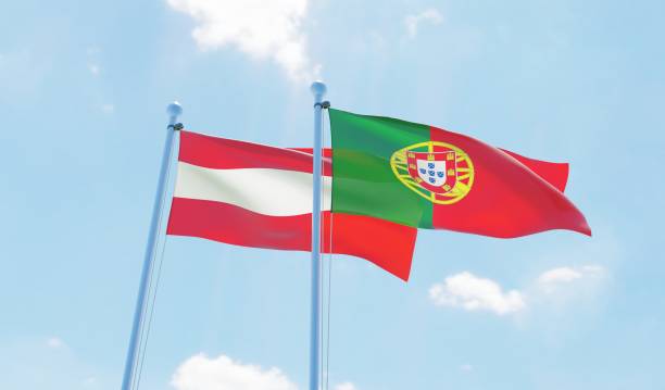 istock Portugal and Austria, two flags waving against blue sky 1129374359
