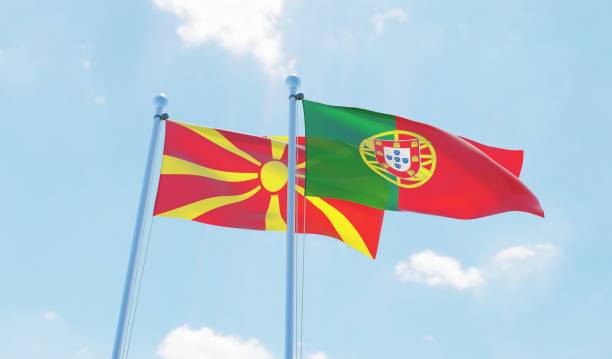 istock Portugal and Macedonia, two flags waving against blue sky 1129374616