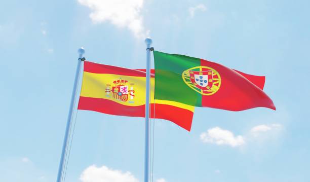 Portugal and Spain, two flags waving against blue sky