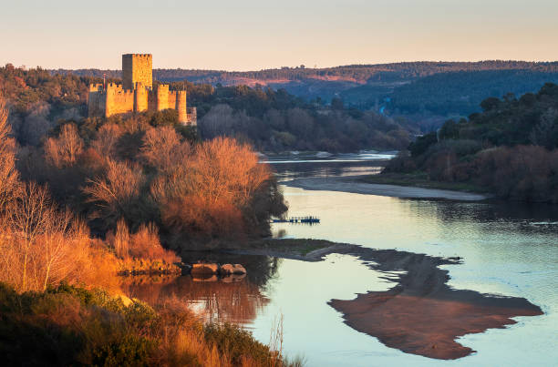 Almourol, Portugal - January 12, 2019: 12th century Almourol castle and Tagus river at sunset on a winter day. The Almourol castle is situated on an island in the Tagus river, whose flow is reduced due to the lack of rain this winter.
